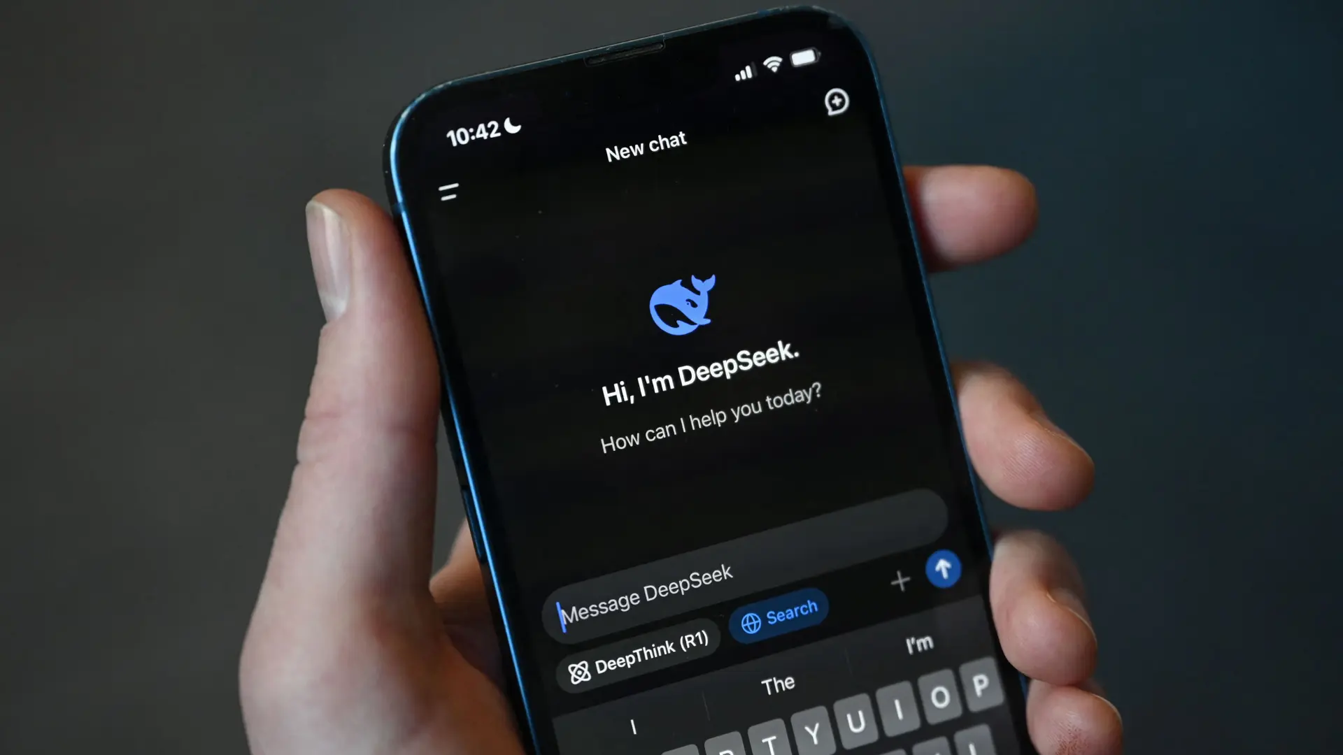 User holding a smartphone with the DeepSeek AI assistant app demonstrating AI-powered tools